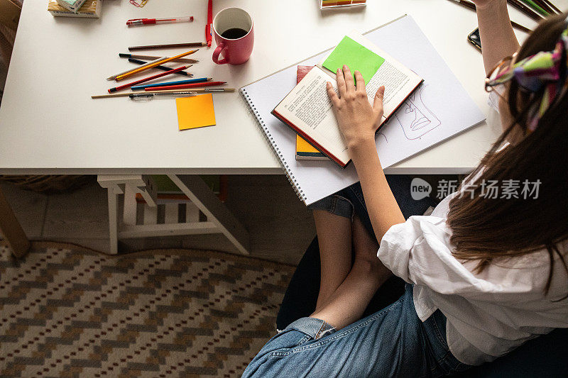 年轻女子坐在书桌前，在家学习