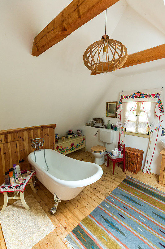 宽敞的浴室内饰有木地板和独立式浴缸
