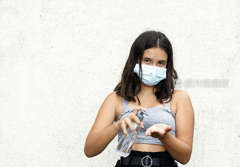 十几岁的女孩正在用消毒凝胶消毒她的手