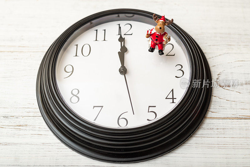 赠送礼物的时间概念。时钟显示没有一分钟到12点和新年的玩具人物。新年前一分钟。