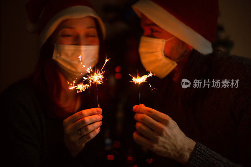 戴着防护面具的情侣在家里一起庆祝新年。