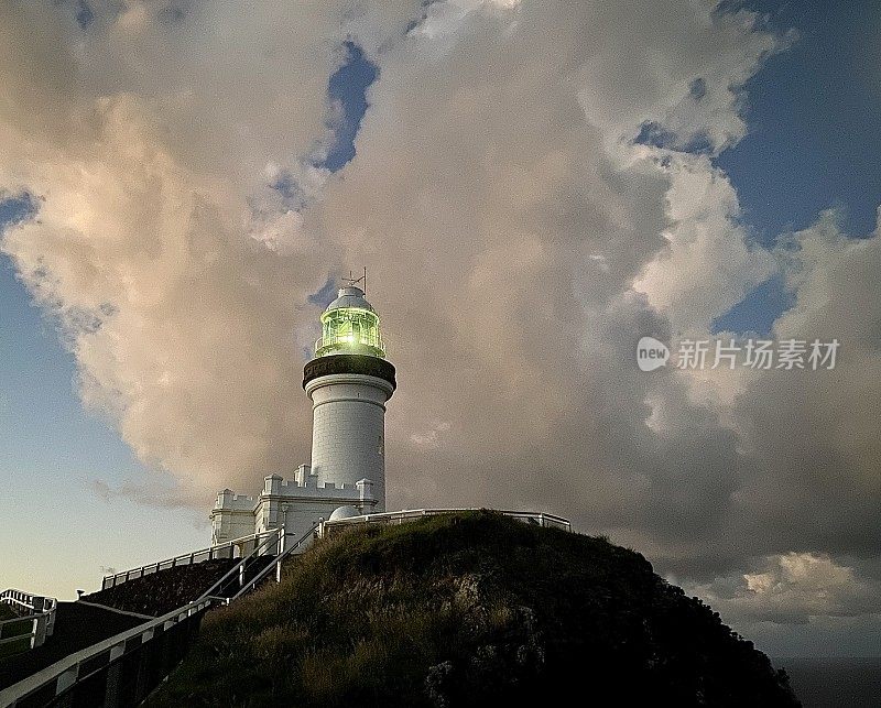 灯塔在多云的天空下照亮日落