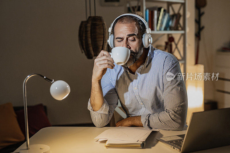 劳累的男人在工作到很晚的时候喝咖啡