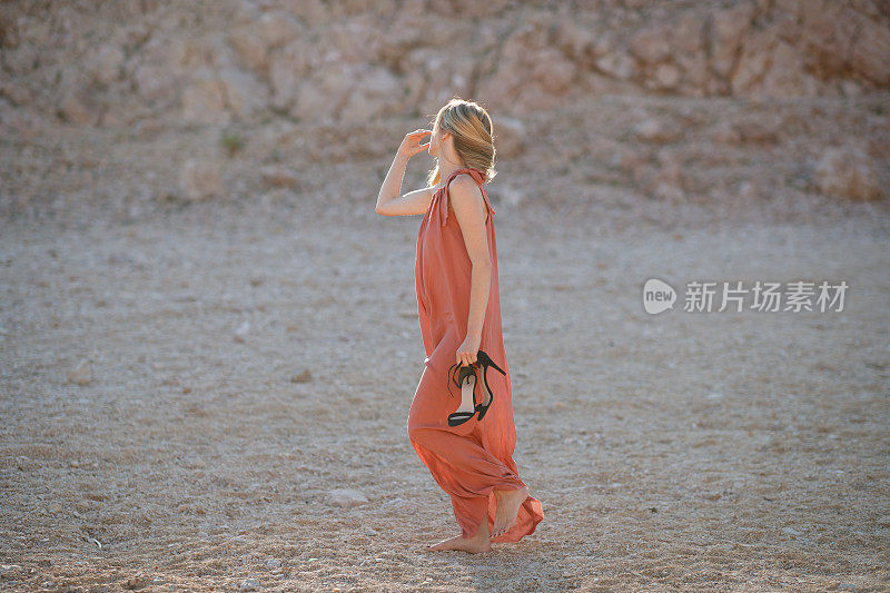 美丽的女人穿着夏天的衣服，赤脚在石头沙漠里独自享受时光