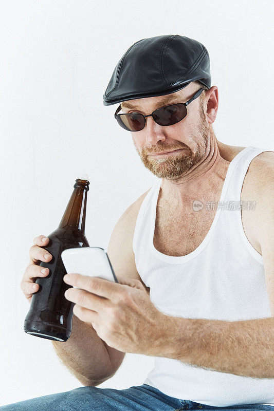 一个成熟的男人一边喝啤酒一边用智能手机
