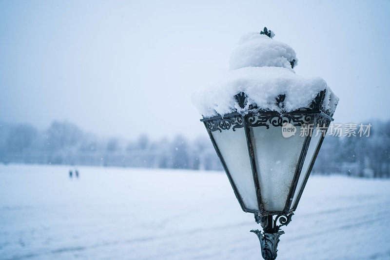 寒冷的日子里，城市公园里的路灯下着雪花