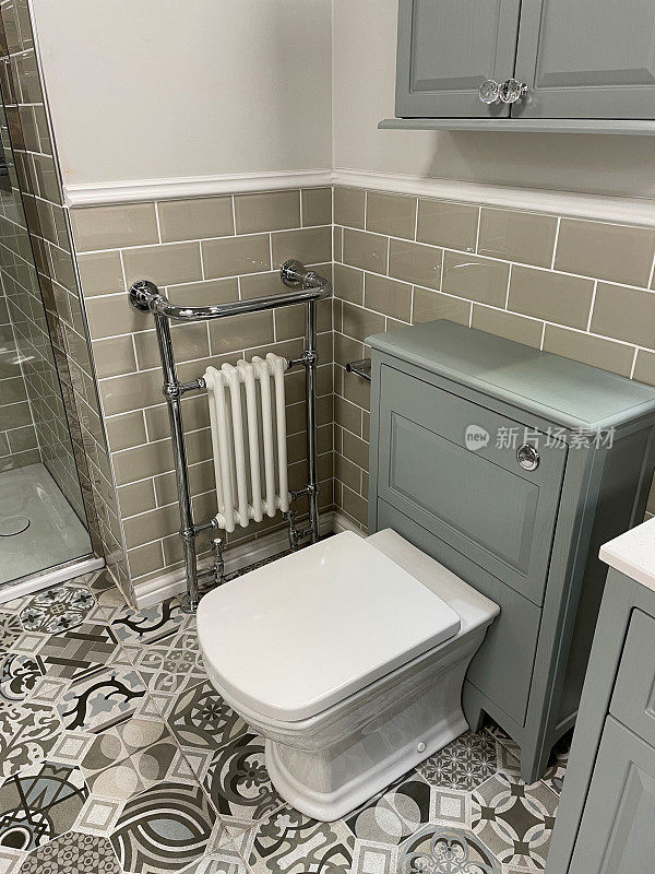 现代浴室的形象与白色，方形卫生间水箱隐藏在灰色梳妆台，铬毛巾栏杆散热器挂在墙上的光滑瓷砖，棕色瓷砖，独立淋浴间，有图案的地砖