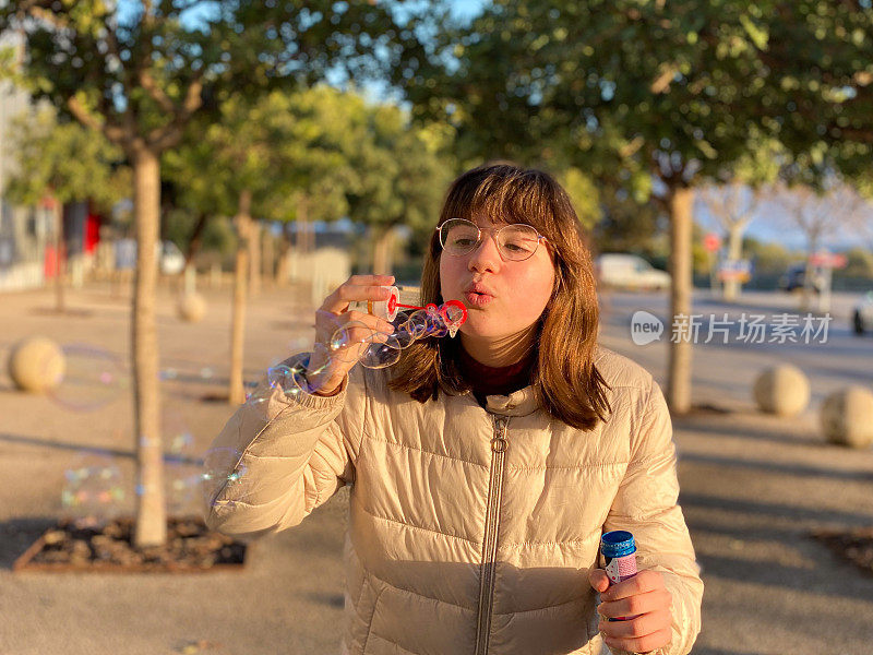 一个十几岁的女孩在街上吹肥皂泡