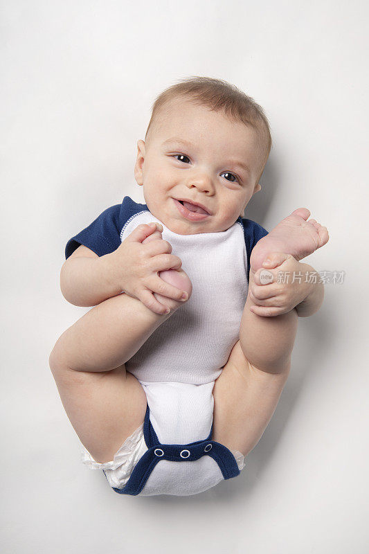 六个月大的男婴笑着抓脚