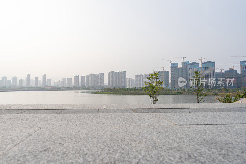 雾霾天气下湖畔的现代城市天际线