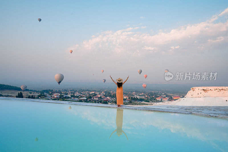 在土耳其德尼兹利的Pamukkale石灰华泳池里，美丽的游客女孩在观看热气球时打开了她的眼睛