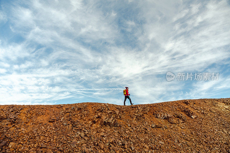 年轻的女徒步旅行者走在山崖上