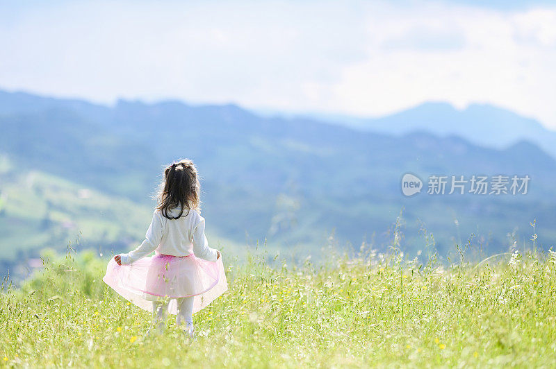 一个蹒跚学步的小女孩和家人一起徒步旅行后，在意大利的山丘上看着山景城。快乐暑假，健康生活理念。与自然统一。行动自由