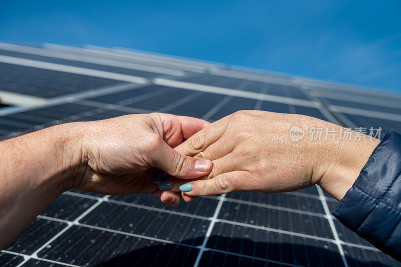 两对手在太阳能板的背景下成交后握手。