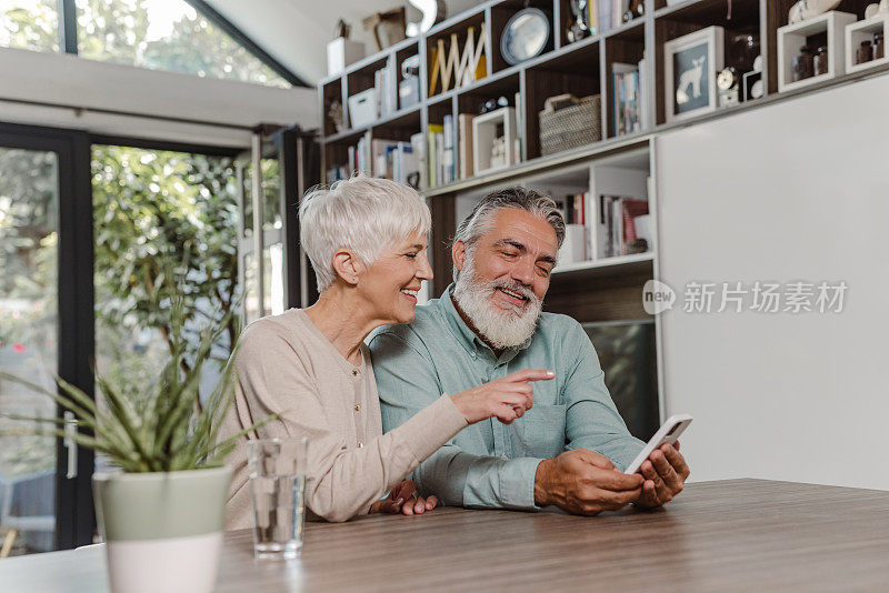 快乐的老年人在家里使用智能手机