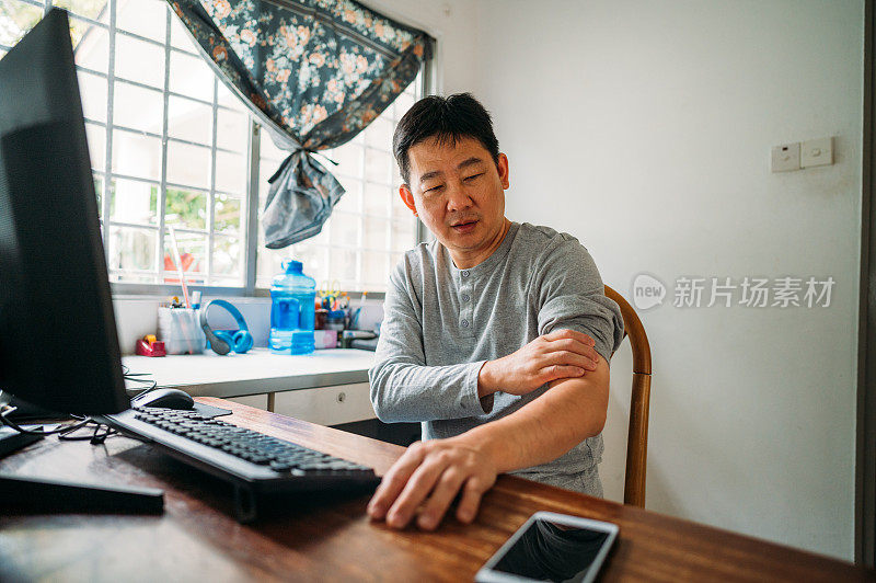 一名亚裔华人男子在家办公时手肘疼痛