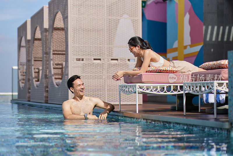 亚洲夫妇在酒店泳池边聊天