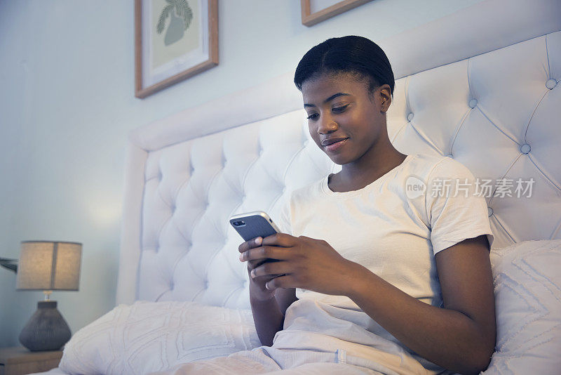 卧室电话，放松的夜晚和黑人女性阅读博客故事，新闻文章或网上购物，研究或滚动feed。家里的手机，床和非洲人发短信，搜索或发布到媒体应用程序