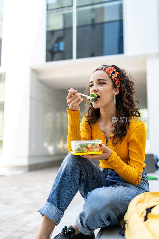 年轻女子在户外吃沙拉