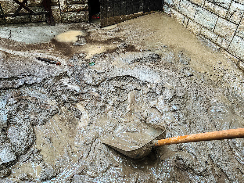 用铲子清除洪水后的河道淤泥残渣