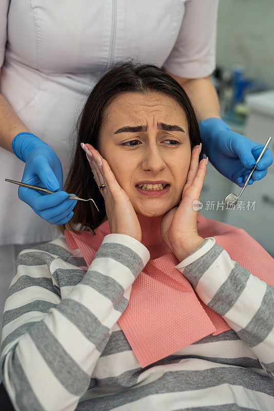 牙医使用牙科工具为她的女性客户进行口腔检查和检查蛀牙和牙龈
