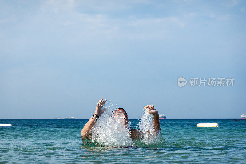 他用手在海里泼水。一个夏天的早晨。忒涅多斯岛。爱琴海北部，12岁的帅哥。长头发的