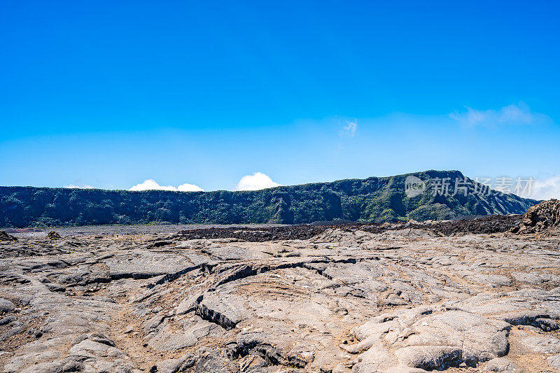 粗糙的自然火山景观，黑色凝固熔岩流结束于凝固熔岩场，背景为火山口边缘。欧洲法国留尼汪岛的富尔奈斯峰。