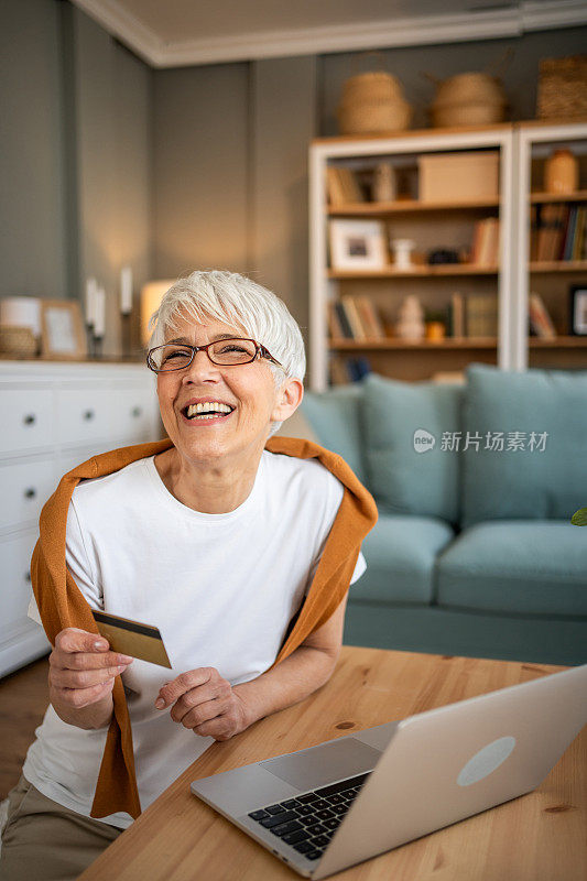 快乐的退休妇女使用平板电脑进行网上银行或网上购物