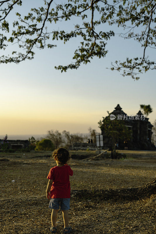一个亚洲小男孩在日惹的拉图博科神庙美丽的日落下，在公园的草坪上奔跑。享受大自然和夏日户外。童年的生活方式，无忧无虑的自由观念