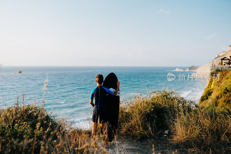 小男孩站在观景台上看着海浪