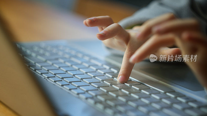 男孩用手敲击笔记本电脑键盘的特写。孩子使用电脑进行网上远程教育。在家在线学习。