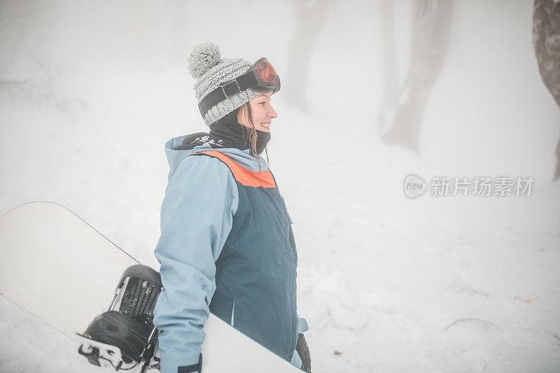 微笑的女滑雪板运动员准备在山上骑滑雪板。她喜欢雪地活动和冬季运动