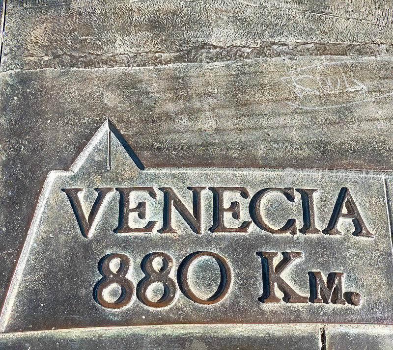 带有指示箭头的金属标志，上面用西班牙语写着威尼斯的名字，你还可以看到它离巴塞罗那省有多少公里。