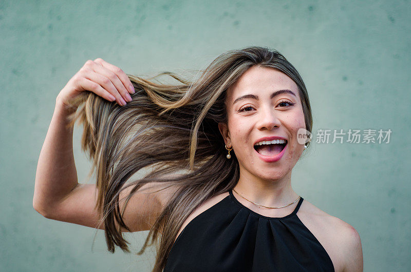 美丽的年轻女子的肖像玩她的头发在灰色背景