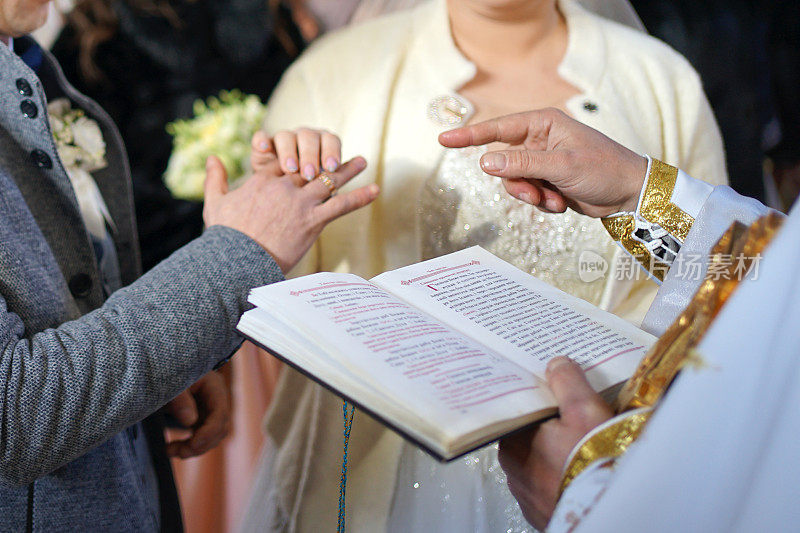 牧师把结婚戒指戴在新婚夫妇的指尖上，然后他们把结婚戒指戴在整个手指上。