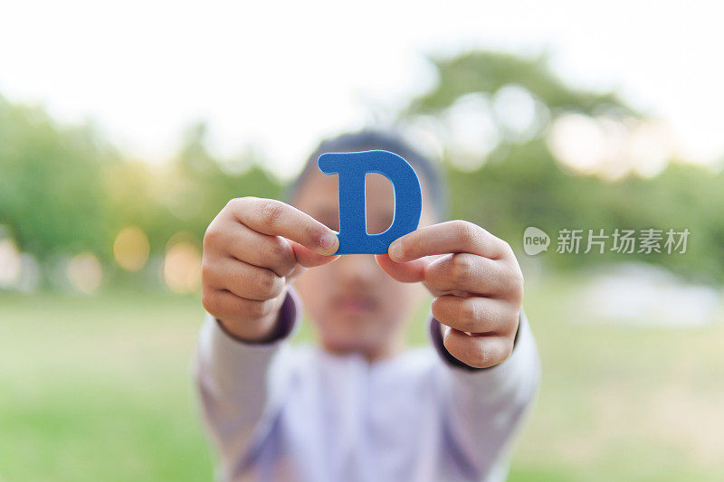 小孩拿着字母“D”