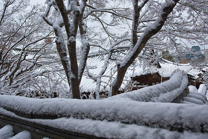 雪覆盖了韩国传统的石墙和屋顶瓦