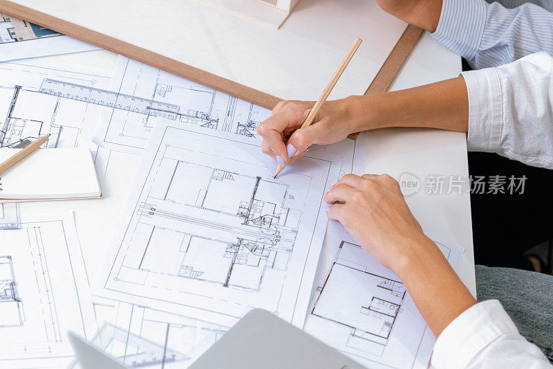建筑师在同事丈量房屋模型的同时手绘蓝图。完美的。