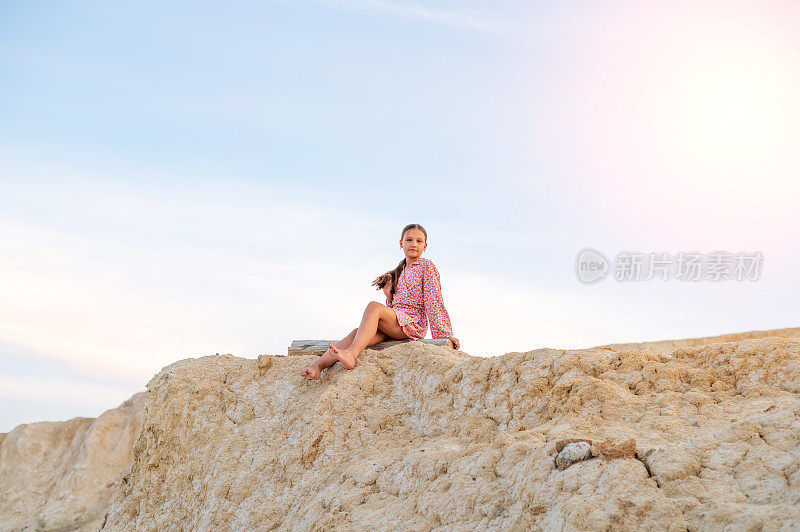 十几岁的女孩在大自然中休息，一个女孩坐在山边的肖像