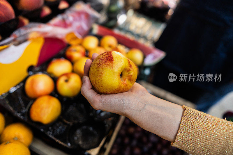 一位女顾客在杂货店挑选苹果的特写