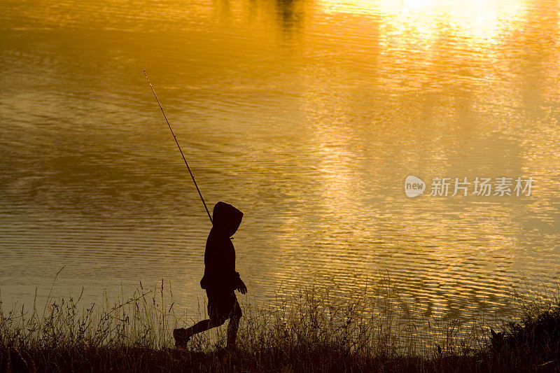 男孩在日落钓鱼