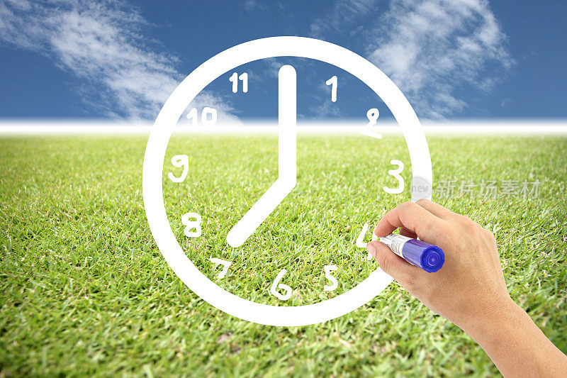 Hand正在草坪和蓝天上画一个时钟。