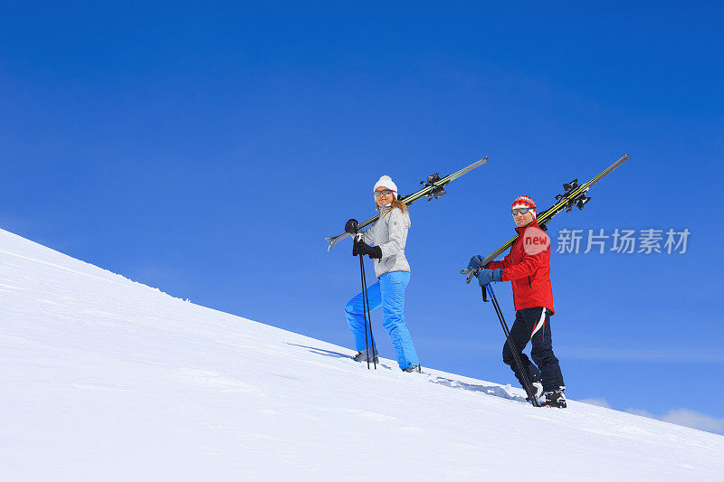 冬季运动朋友，男人和女人滑雪者携带着滑雪板