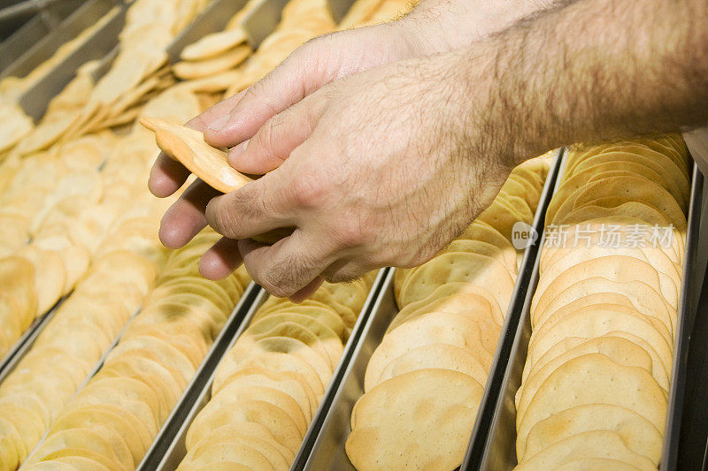 面包师持有一些饼干在生产和包装线。