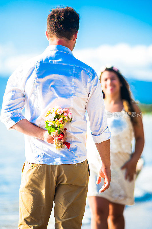 一对年轻的新婚夫妇在阳光明媚的海滩上相爱