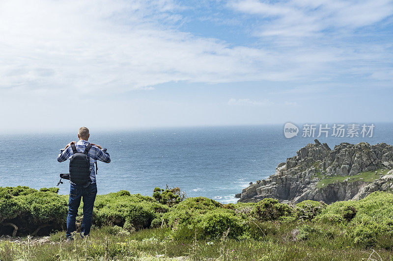 一名男子站在悬崖上欣赏波斯科诺附近的南康沃尔海岸。