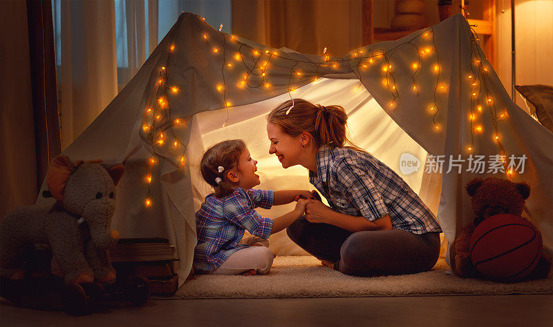 快乐的母女在家里的帐篷里玩