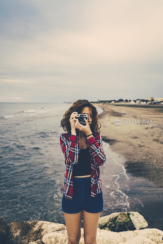 女孩在海上用胶卷相机拍照