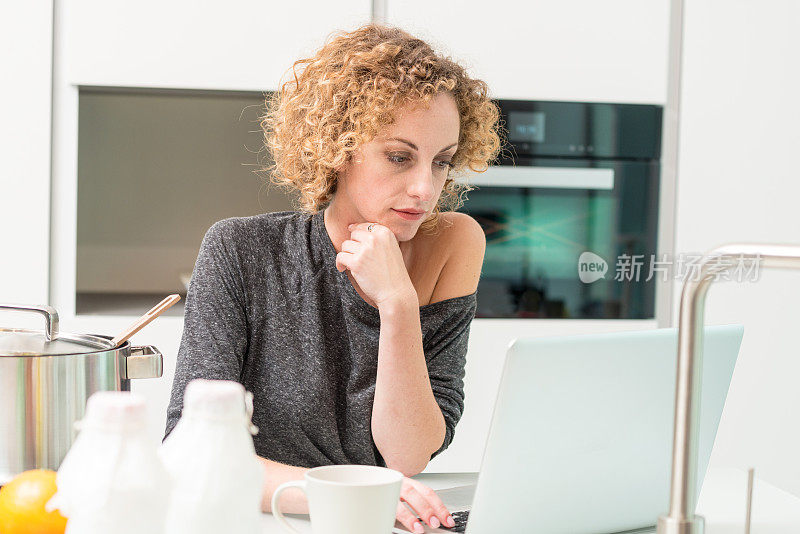 年轻女子在厨房用笔记本电脑