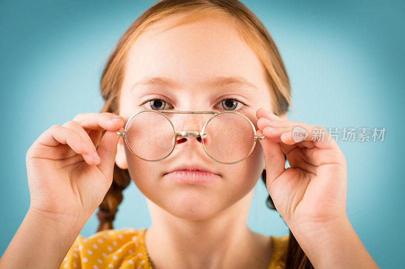 严肃的小女孩看着她的书呆子眼镜